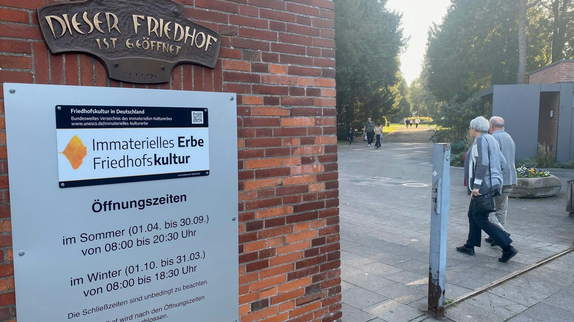 Das Foto zeigt den Eingang zum Friedhof mit der Tafel, die auf die Mitgliedschaft in der Charta hinweist.