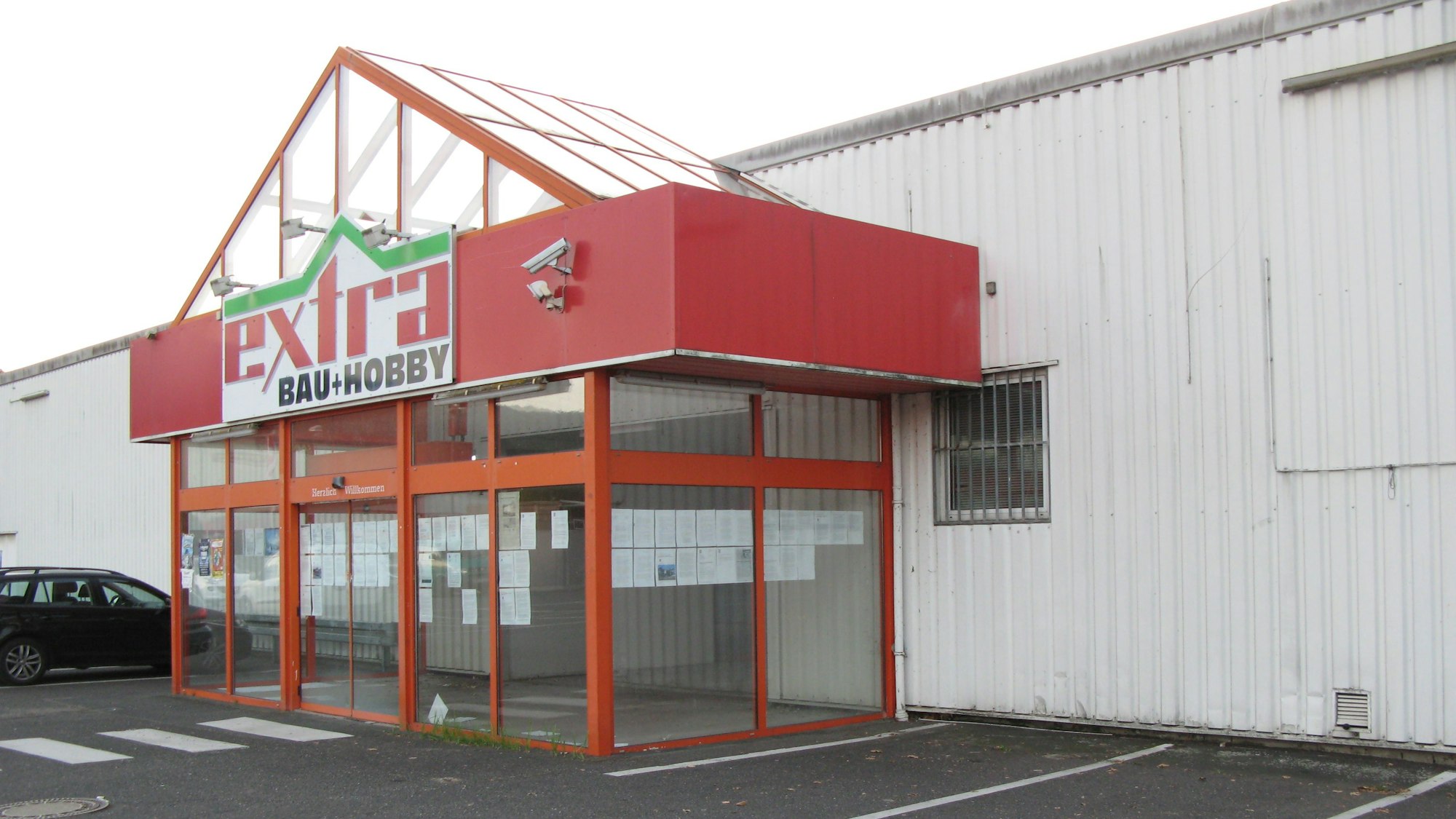 Das Bild zeigt das Eingangsportal eines früheren Baumarkts, der leer steht.