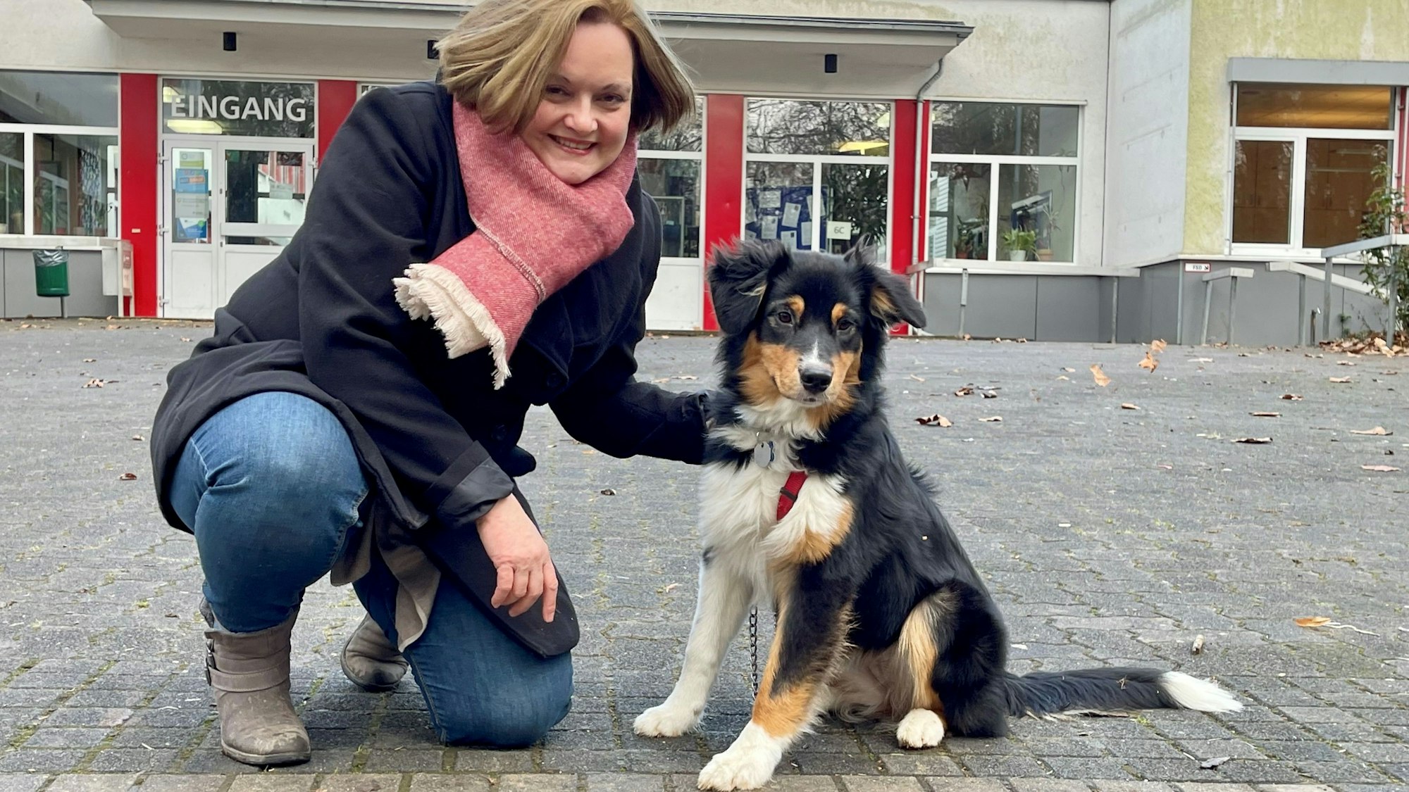 Lotta ist eine Australian Shepherd-Hündin mit schwarzem, braunem und weißem Fell. Neben ihr kniet ihre Besitzerin, die Diplom-Pädagogin Anna Köstering.