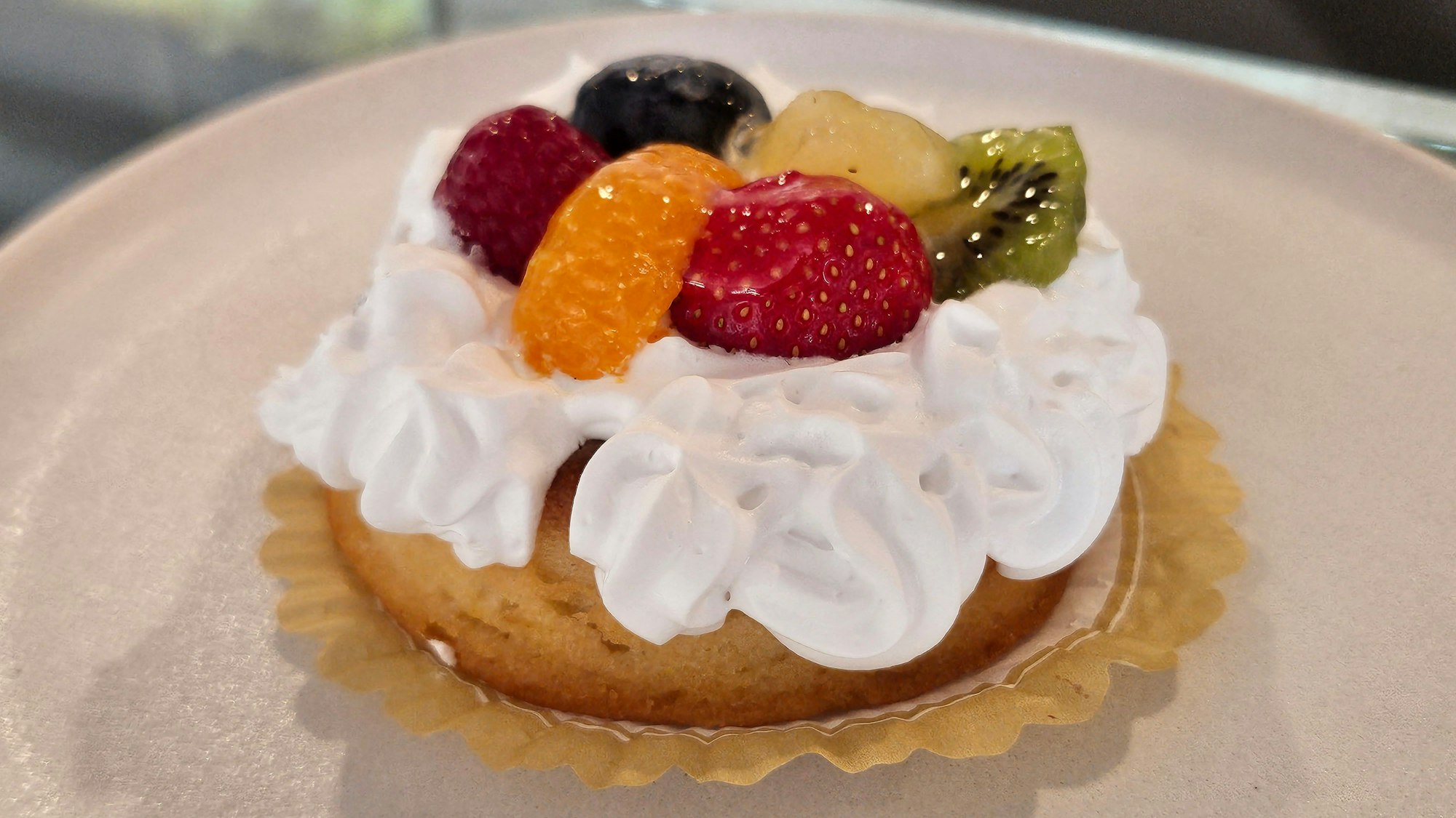 Ein Törtchen mit Sahne und Früchten obendrauf zeigt das Foto.