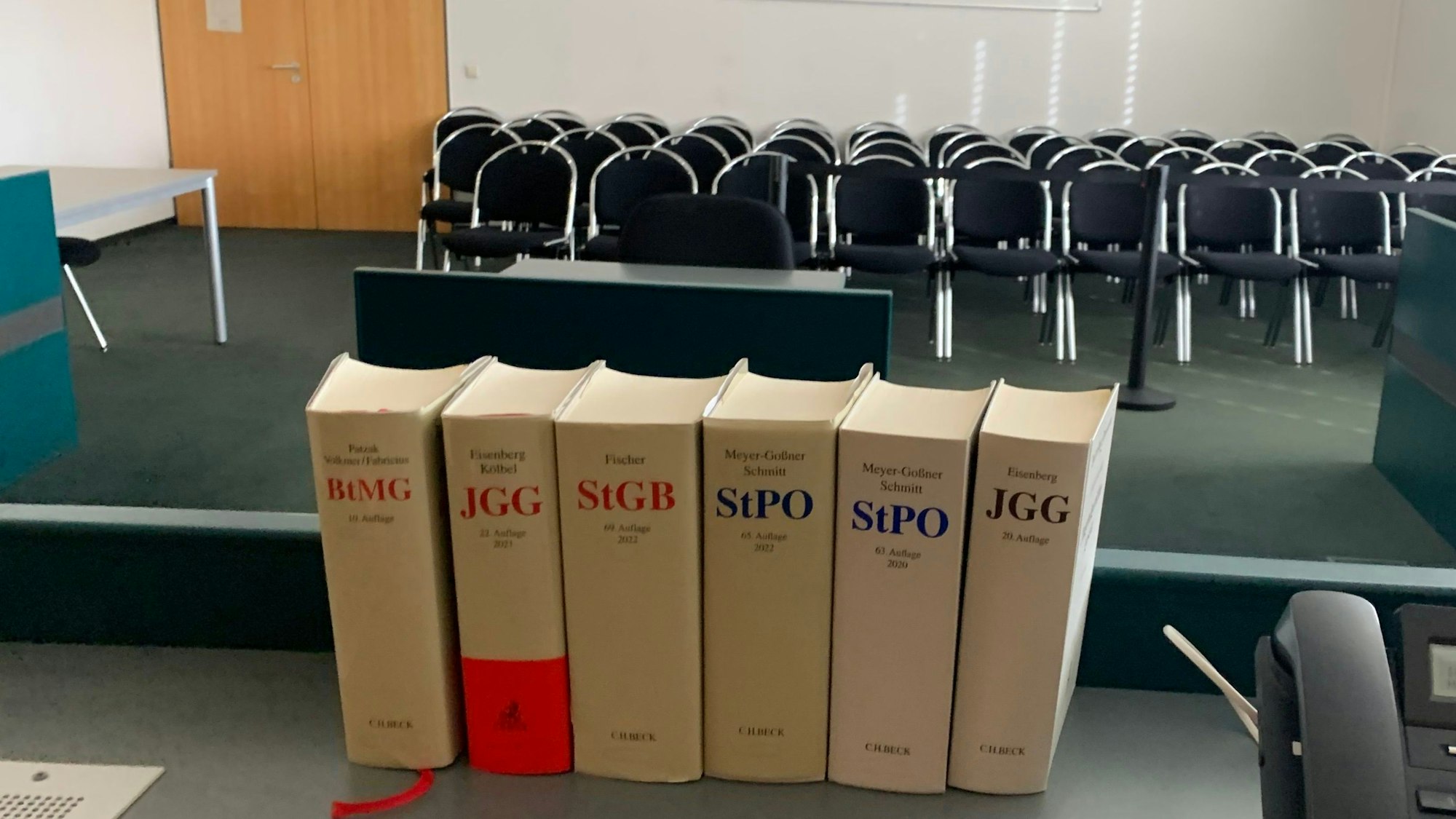 Blick in einen Gerichtssaal, im Vordergrund Bände mit Gesetzestexten.