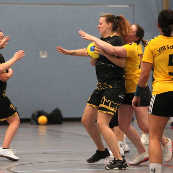 Eine Handballspielerin hat den Ball, eine Gegnerin umklammert sie von hinten.