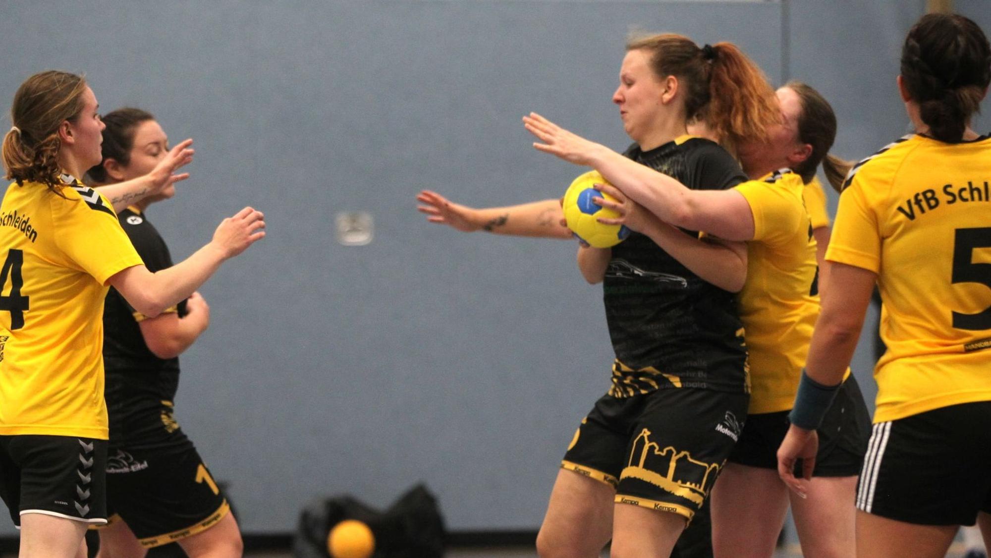 Eine Handballspielerin hat den Ball, eine Gegnerin umklammert sie von hinten.