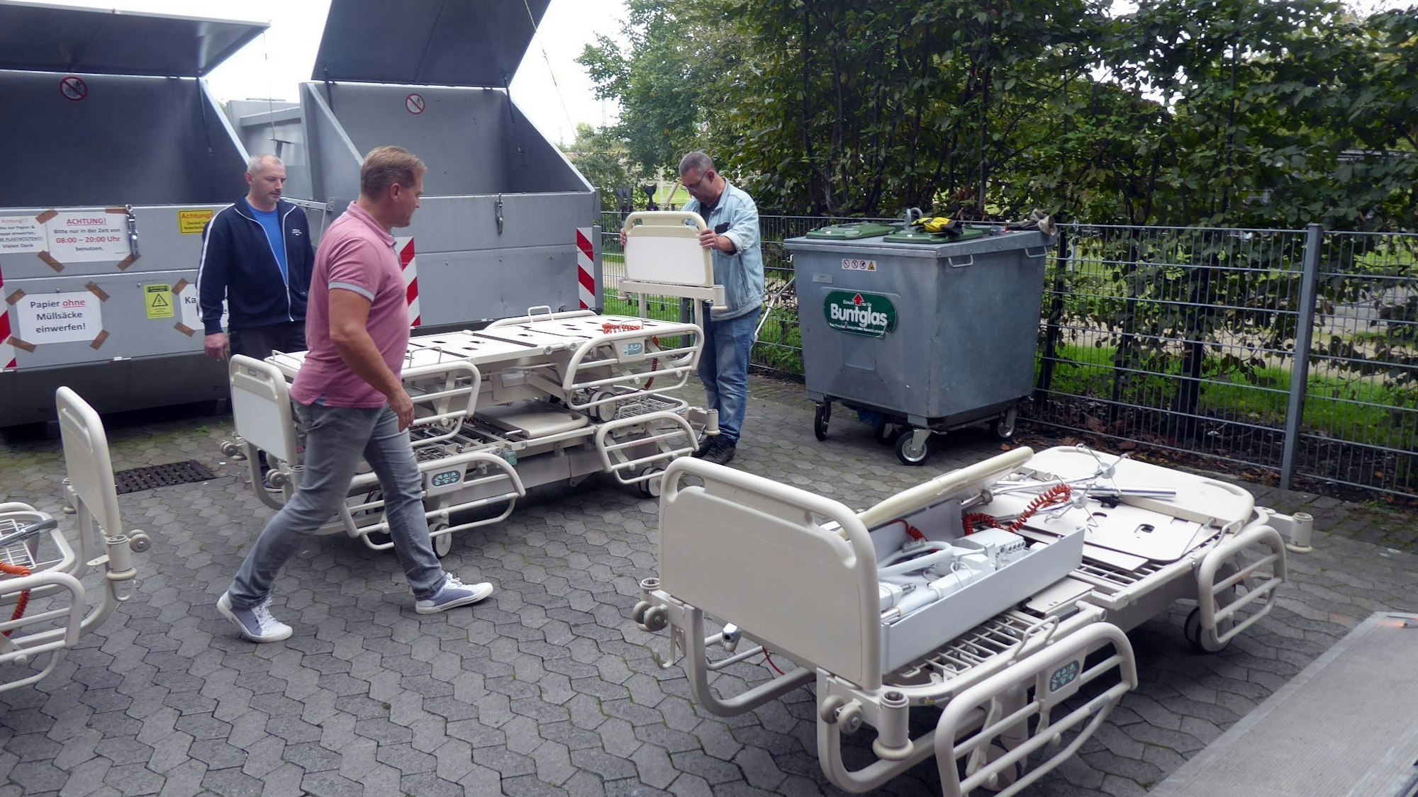 Drei Männer bereiten Pflegebetten für einen Hilfsgütertransport vor.