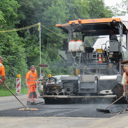 Arbeiter bringen eine Asphaltschicht auf.