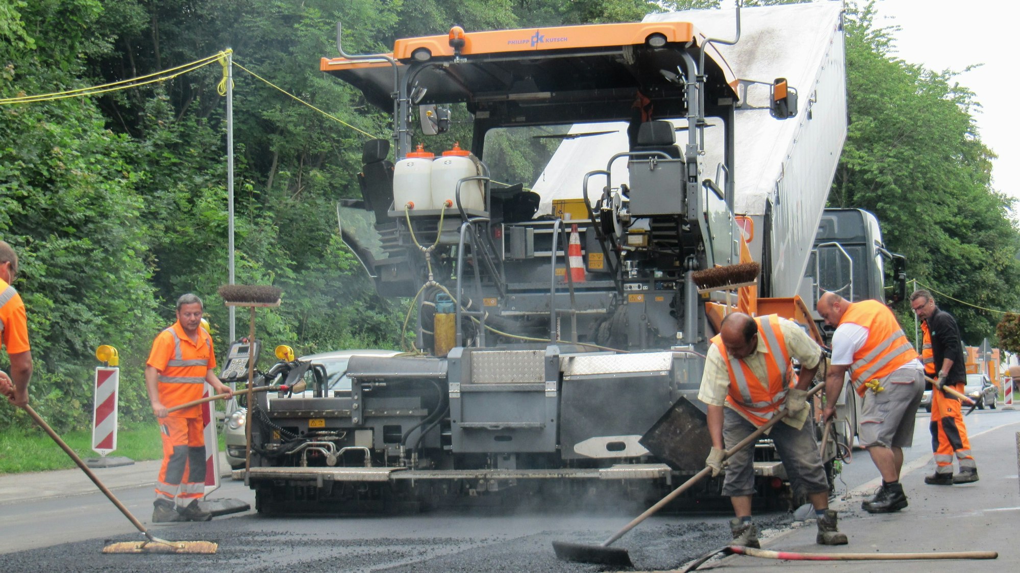 Arbeiter bringen eine Asphaltschicht auf.
