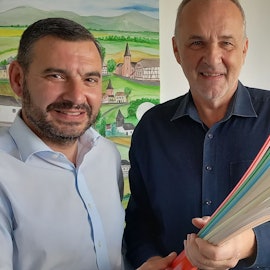 Immer für eine Überraschung gut: Mit dem bnt-Vertriebsleiter Nikolaos Pantios vereinbarte Jörg Schmidt (r.) 2023 kurzfristig den kompletten Glasfaserausbau der noch unversorgten Wachtberg Orte als Nullsummenspiel für die Gemeinde.