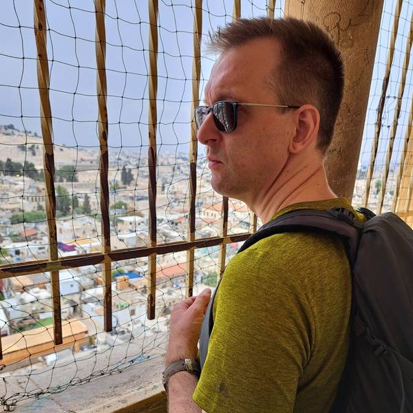 Pastor Oliver Dannenberg steht an der Erlöserkirche in Jerusalem und blickt durch ein Gitter auf die Stadt.