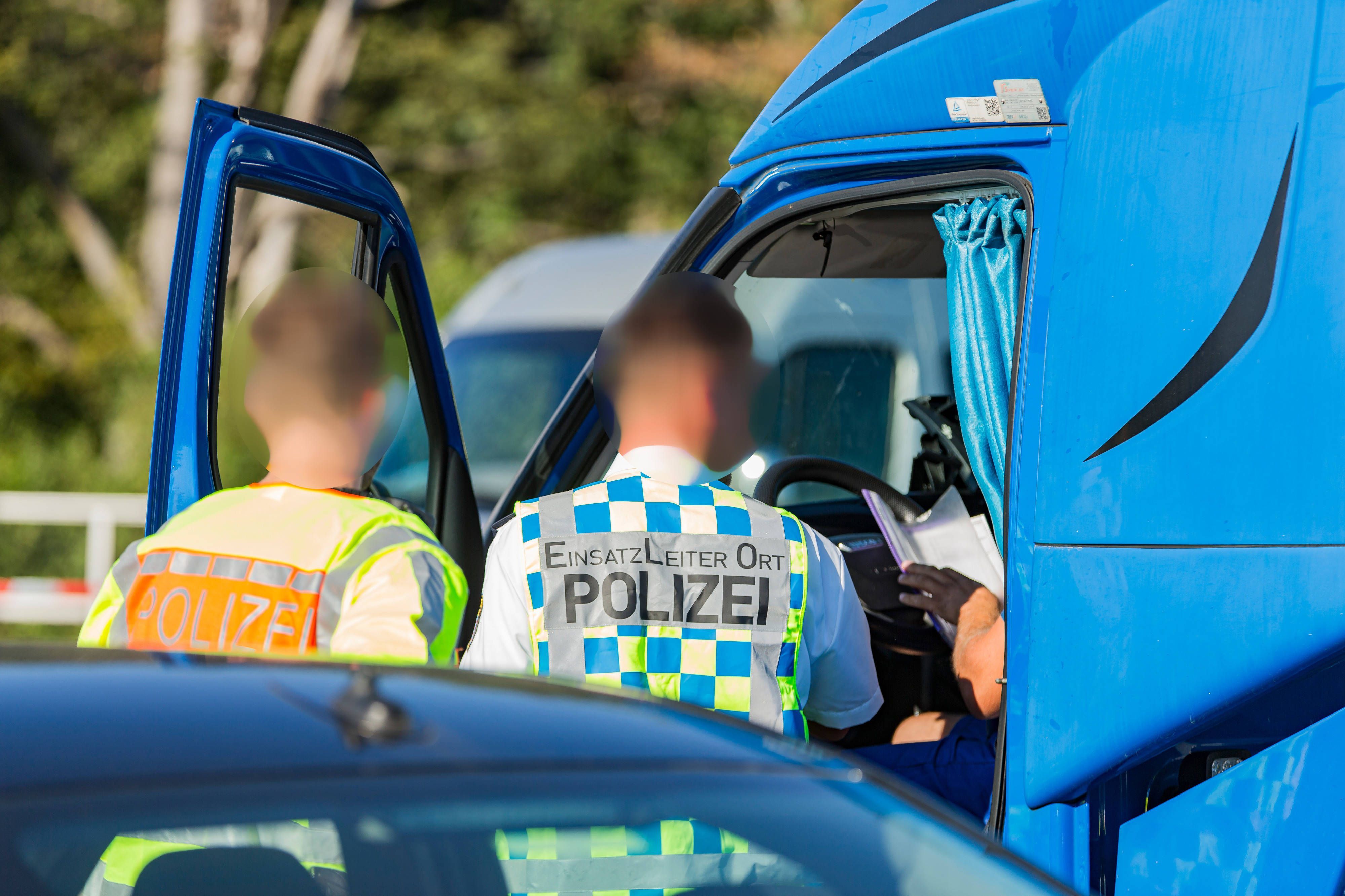 Polizisten kontrollieren das Führerhaus und einen Fahrer eines Lkw auf einer Autobahn. Bei Böblingen auf der A81 hat ein Lkw-Fahrer sein Fahrzeug auf dem Autobahn-Mittelstreifen abgestellt und ein Nickerchen gehalten. (Symbolbild)