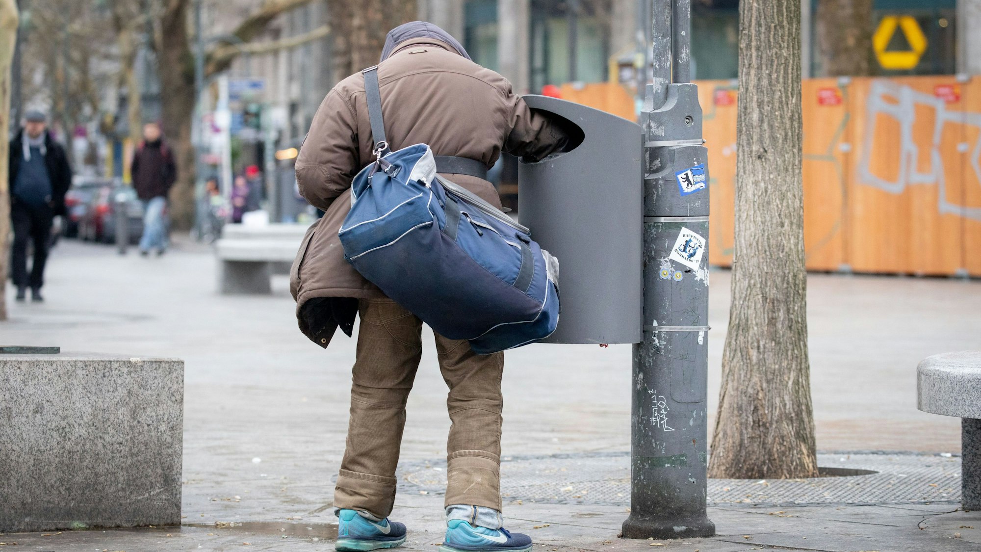 Ein Flaschensammler greift in eine Mülltonne. Sozialverbände haben in NRW mehr Einsatz gegen Armut und Einsamkeit angemahnt. In vielen Städten des Ruhrgebiets sei die Lage dramatisch. In Bochum liege der Anteil armutsgefährdeter Kinder mit 27 Prozent so hoch wie nie zuvor. Gelsenkirchen komme mit 41,5 Prozent auf die höchste Quote deutschlandweit.