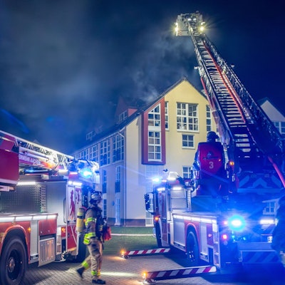 Einsatzkräfte der Feuerwehr löschen den Brand in einem Wohnhaus. Bei einem Brand in einem Mehrfamilienhaus in Aachen sind sieben Menschen verletzt worden. Alle erlitten leichte Rauchgasvergiftungen, zwei von ihnen wurden ins Krankenhaus gebracht, wie die Polizei in der Nacht zu Donnerstag mitteilte. Das Feuer war am Mittwochabend im Dachstuhl des vierstöckigen Gebäudes ausgebrochen. Die Brandursache war zunächst unklar, die Höhe des Schadens ebenfalls.