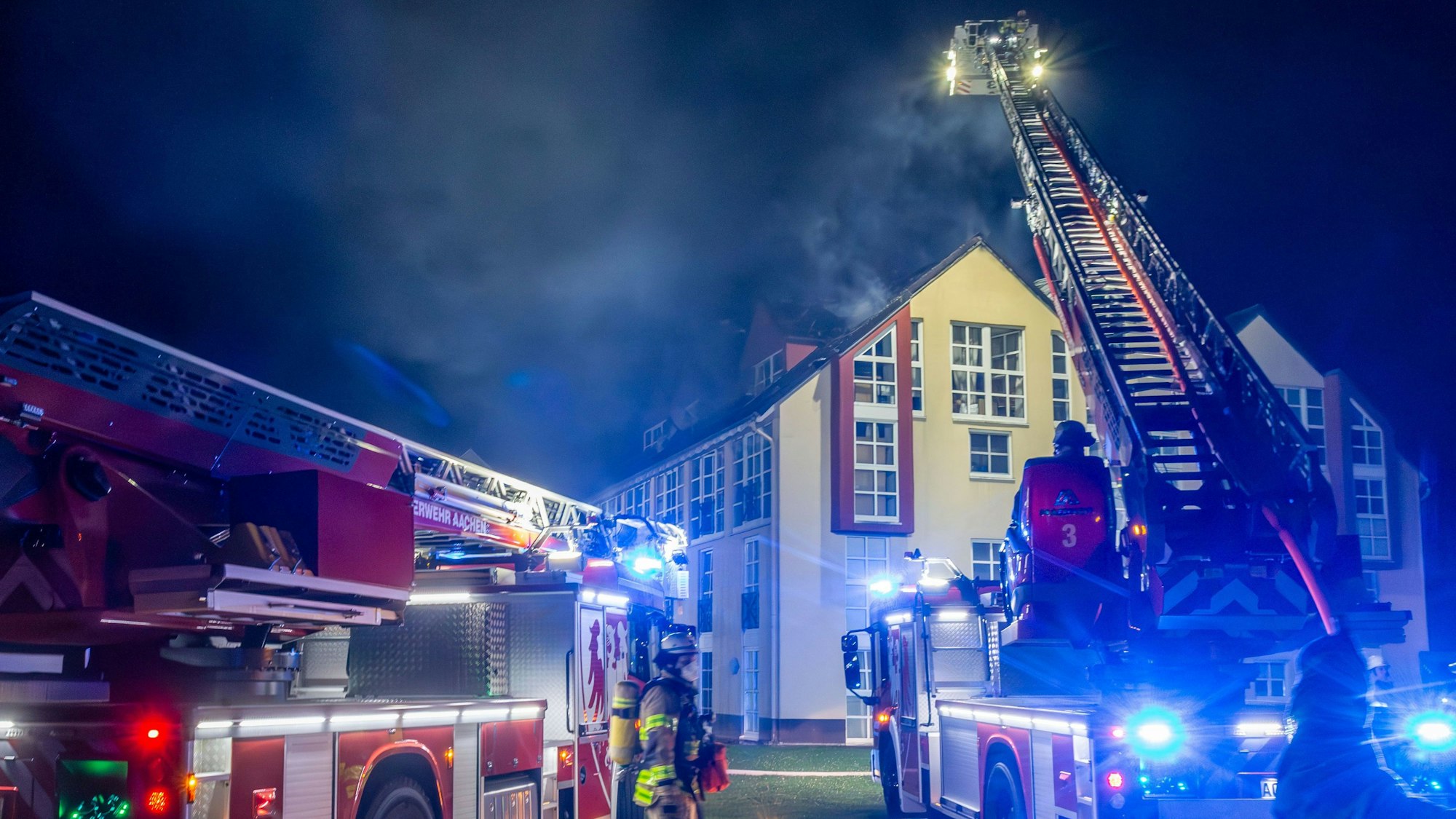 Einsatzkräfte der Feuerwehr löschen den Brand in einem Wohnhaus. Bei einem Brand in einem Mehrfamilienhaus in Aachen sind sieben Menschen verletzt worden. Alle erlitten leichte Rauchgasvergiftungen, zwei von ihnen wurden ins Krankenhaus gebracht, wie die Polizei in der Nacht zu Donnerstag mitteilte. Das Feuer war am Mittwochabend im Dachstuhl des vierstöckigen Gebäudes ausgebrochen. Die Brandursache war zunächst unklar, die Höhe des Schadens ebenfalls.