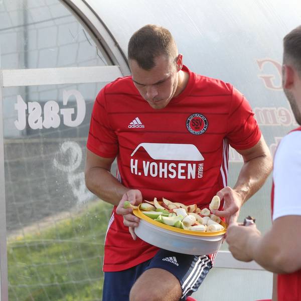 Das Bild zeigt zwei Fußballer des SSV Lommersum, wie sie Obst essen – und einen Schokoriegel.
