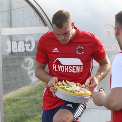 Das Bild zeigt zwei Fußballer des SSV Lommersum, wie sie Obst essen – und einen Schokoriegel.