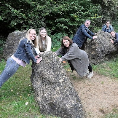Einige Personen demonstrieren an drei Felsblöcken Bewegungsübungen.