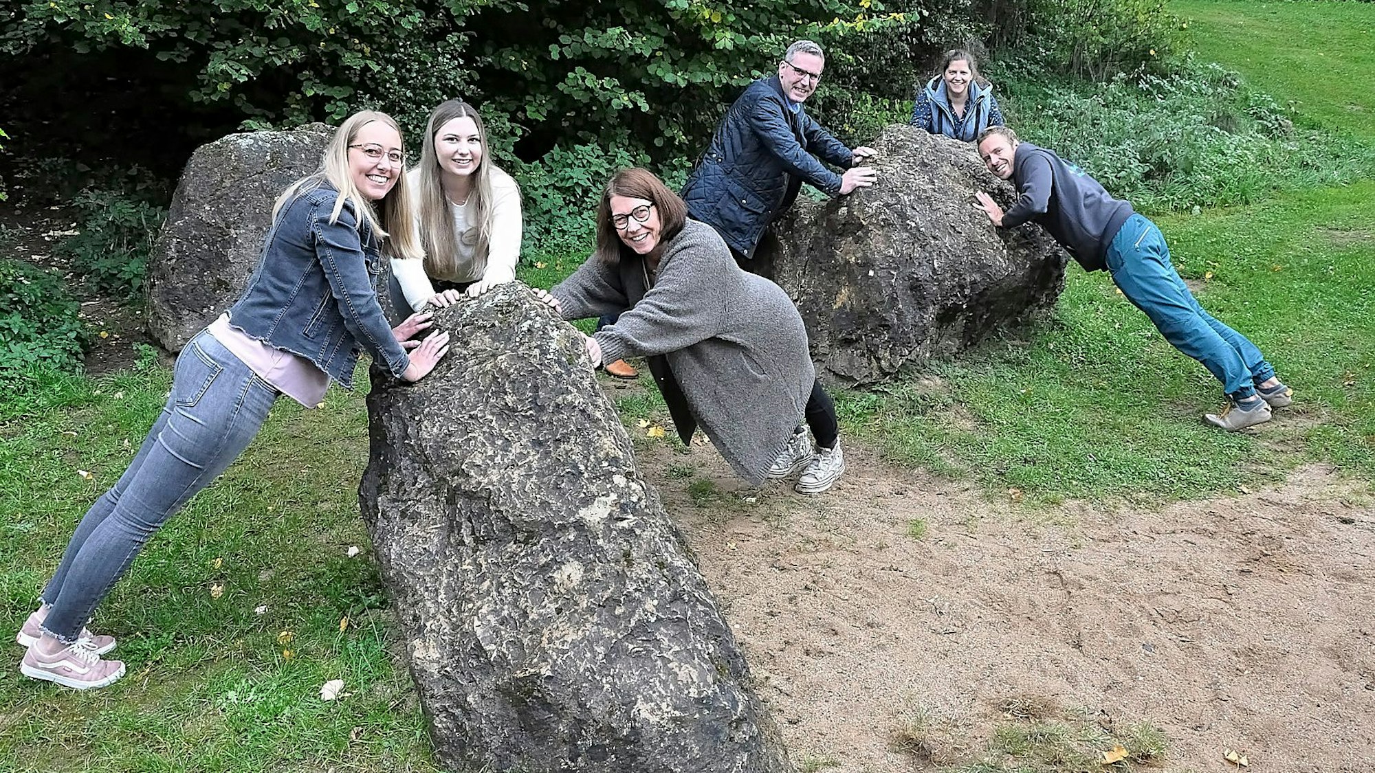 Einige Personen demonstrieren an drei Felsblöcken Bewegungsübungen.