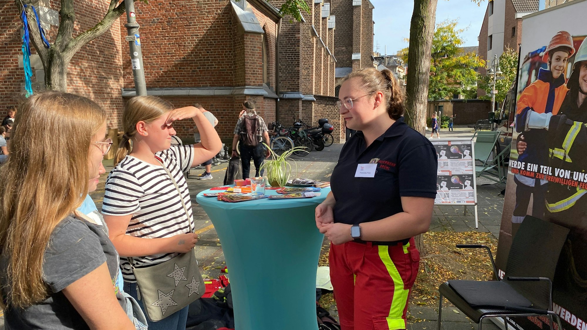 Zu sehen ist Franziska Pohl, die an einem Stehtisch mit zwei Mädchen spricht.