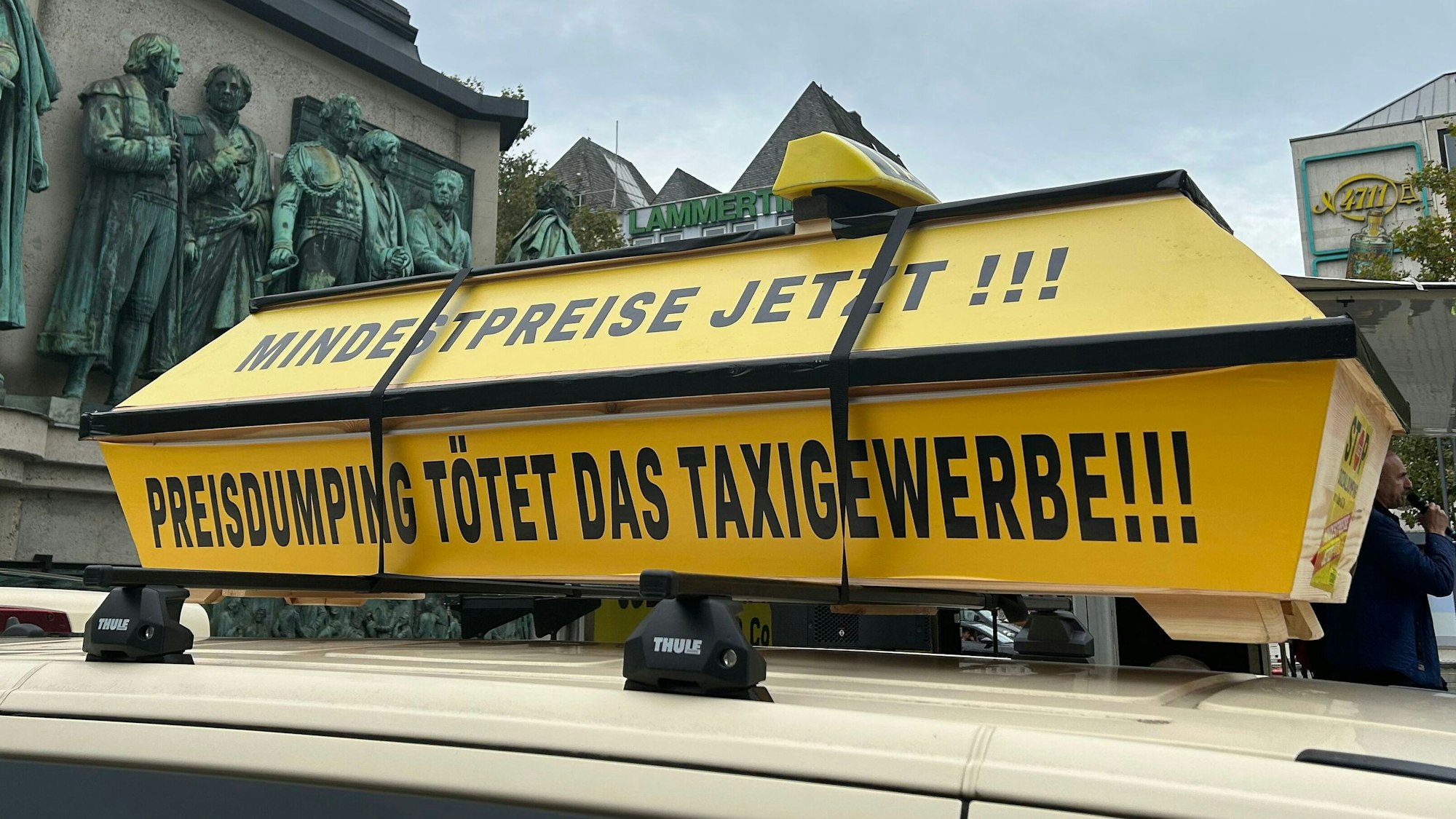 Auf einem gelben Sarg steht „Mindestpreise jetzt, Preisdumping tötet das Taxigewerbe“.