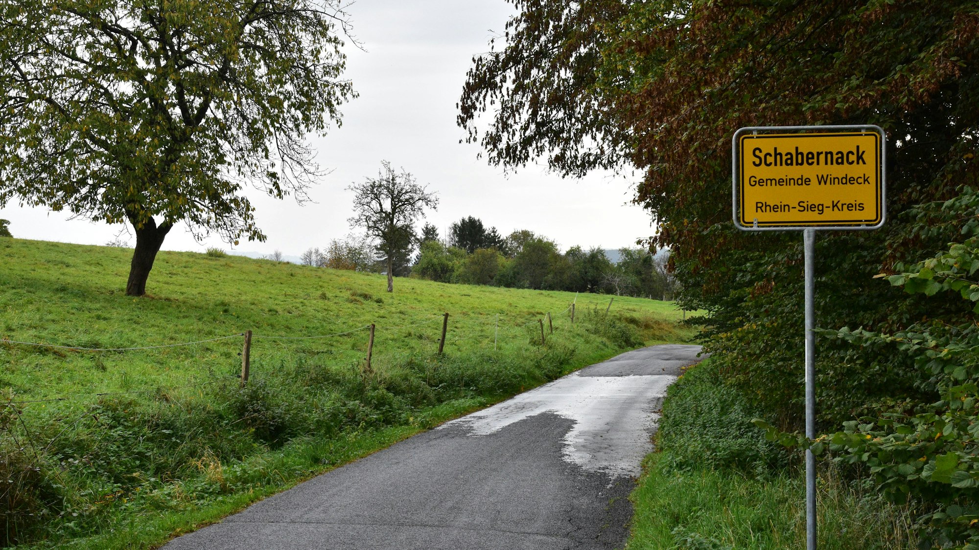 Ein Ortsschild steht an einem Waldweg.