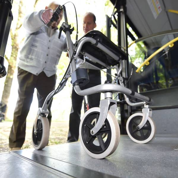 Ein Senior steigt mit einem Rollator in einen Bus.