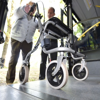 Ein Senior steigt mit einem Rollator in einen Bus.