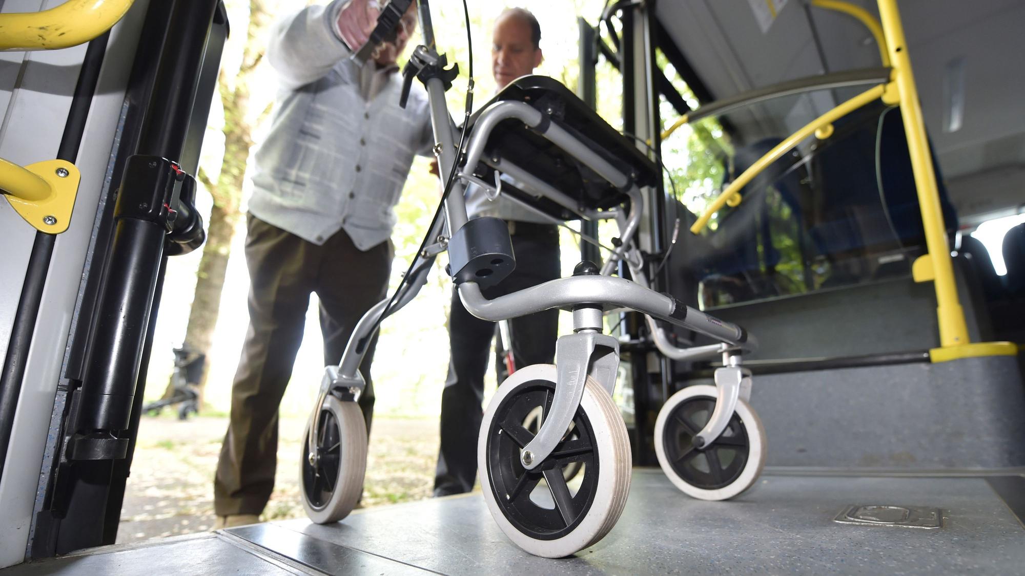 Ein Mann steigt mit seinem Rollator in einen Bus ein.
