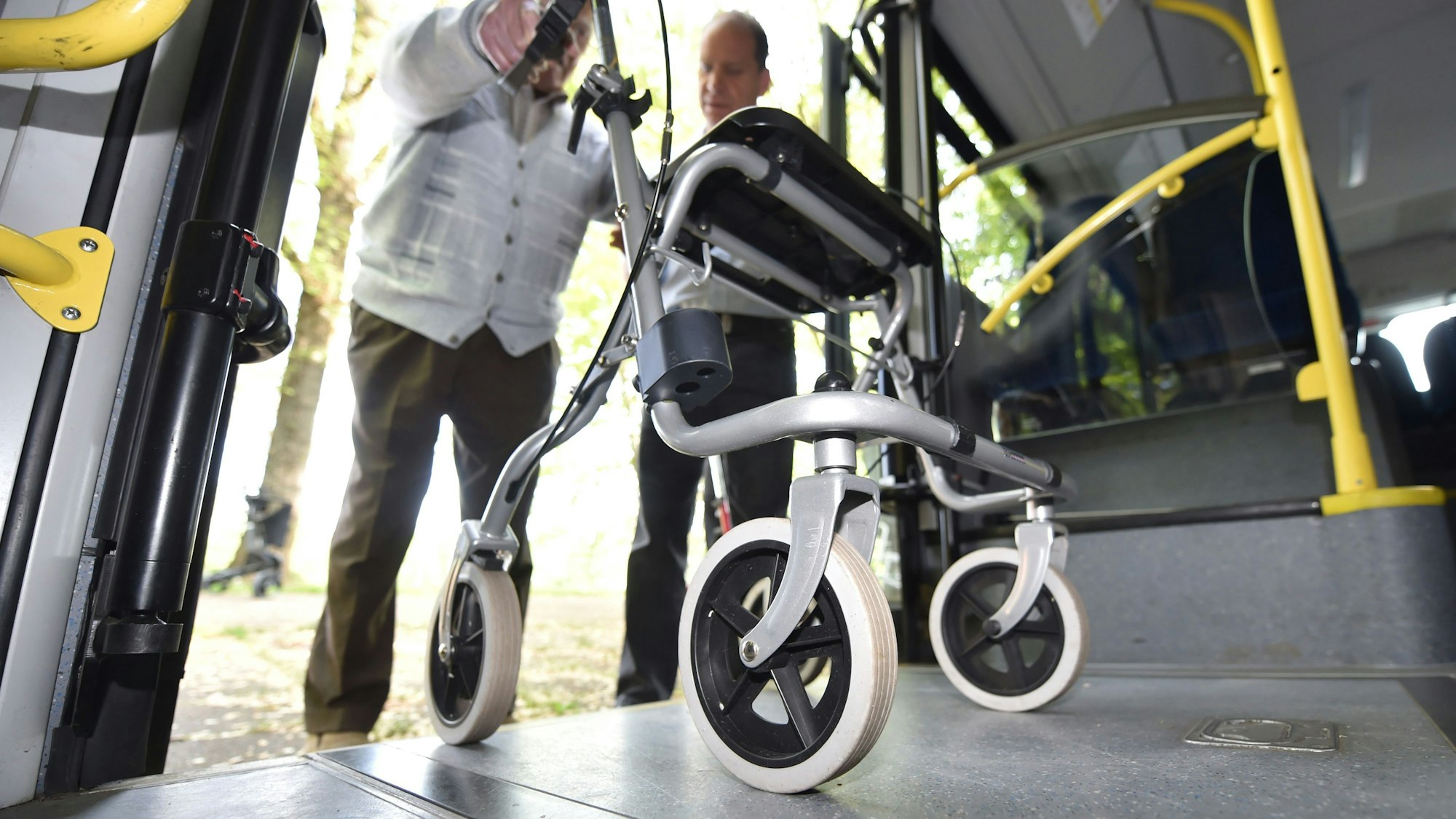 Ein Mann steigt mit seinem Rollator in einen Bus ein.