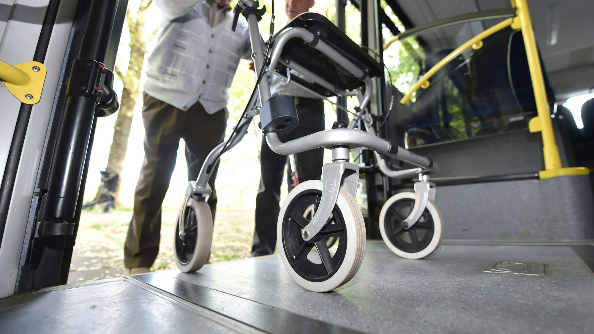 Ein Senior steigt mit einem Rollator in einen Bus.