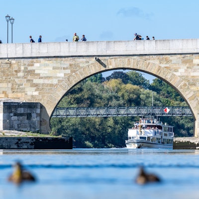 Unter der Steinernen Brücke, die über die Donau verläuft, fährt ein Schiff.(Symbolbild)