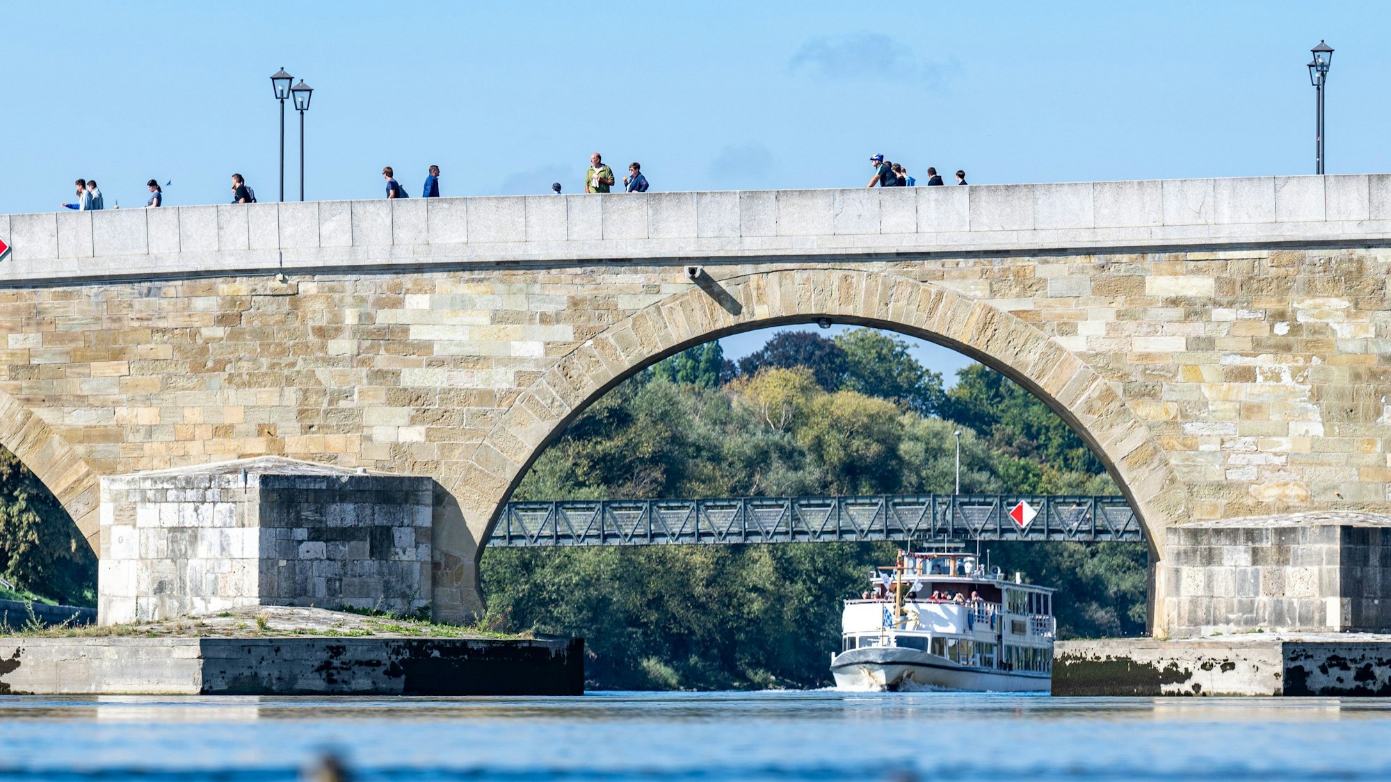 26.09.2023, Bayern, Regensburg: Ein Ausflugsschiff fährt auf der Donau hinter der Steinernen Brücke. (Symbolbild)