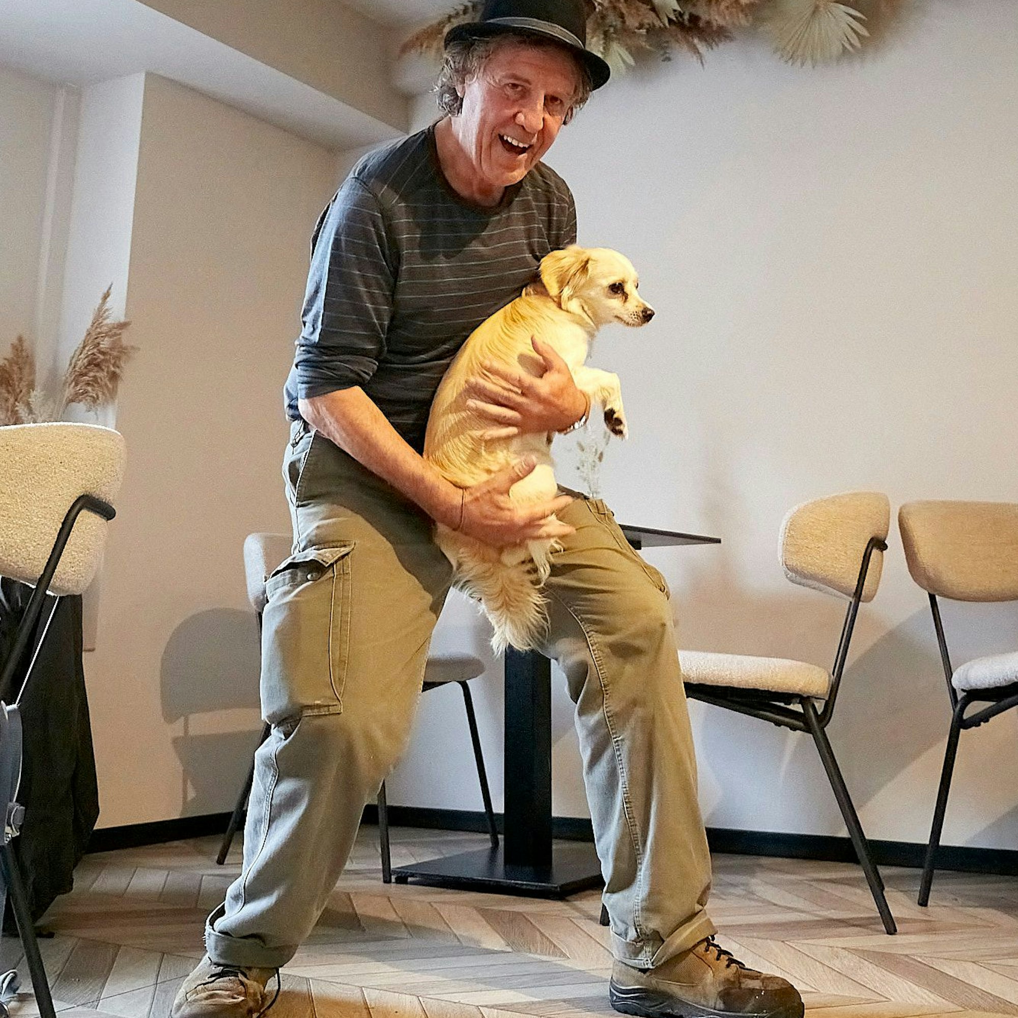 Norbert Scheuer trägt einen etwas zu kleinen Hut auf dem Kopf und einen Hund auf dem Arm.