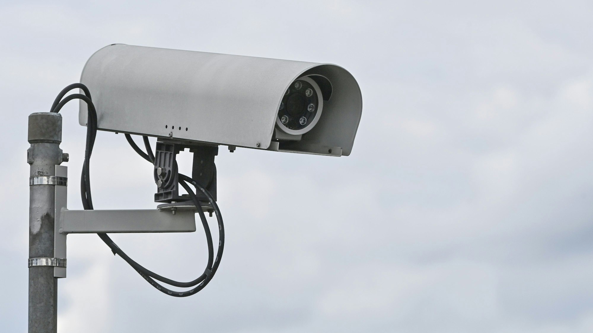 Eine Überwachungskamera vor bewölktem Himmel.