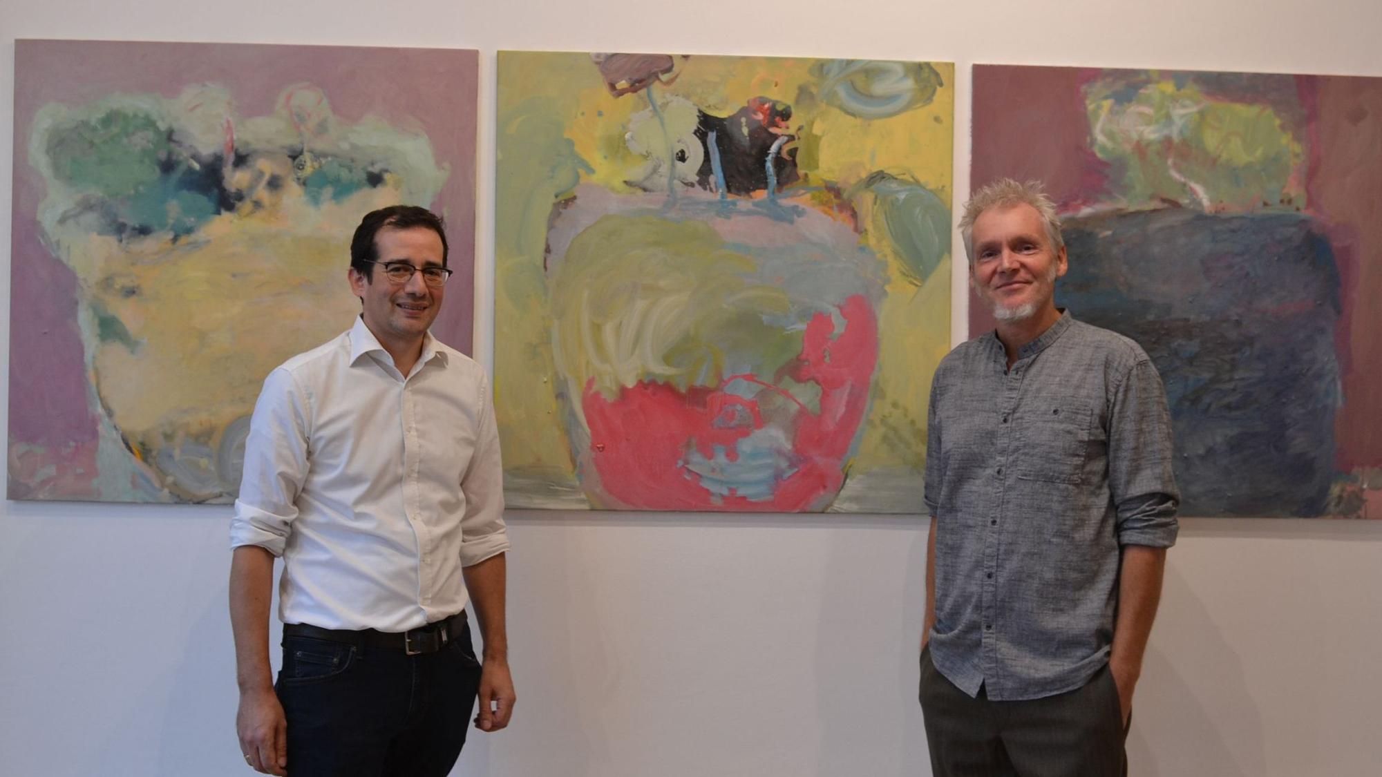 Galerist Stefan Hausen und Künstler Frank Bölter stehen vor einem der Kunstwerke.