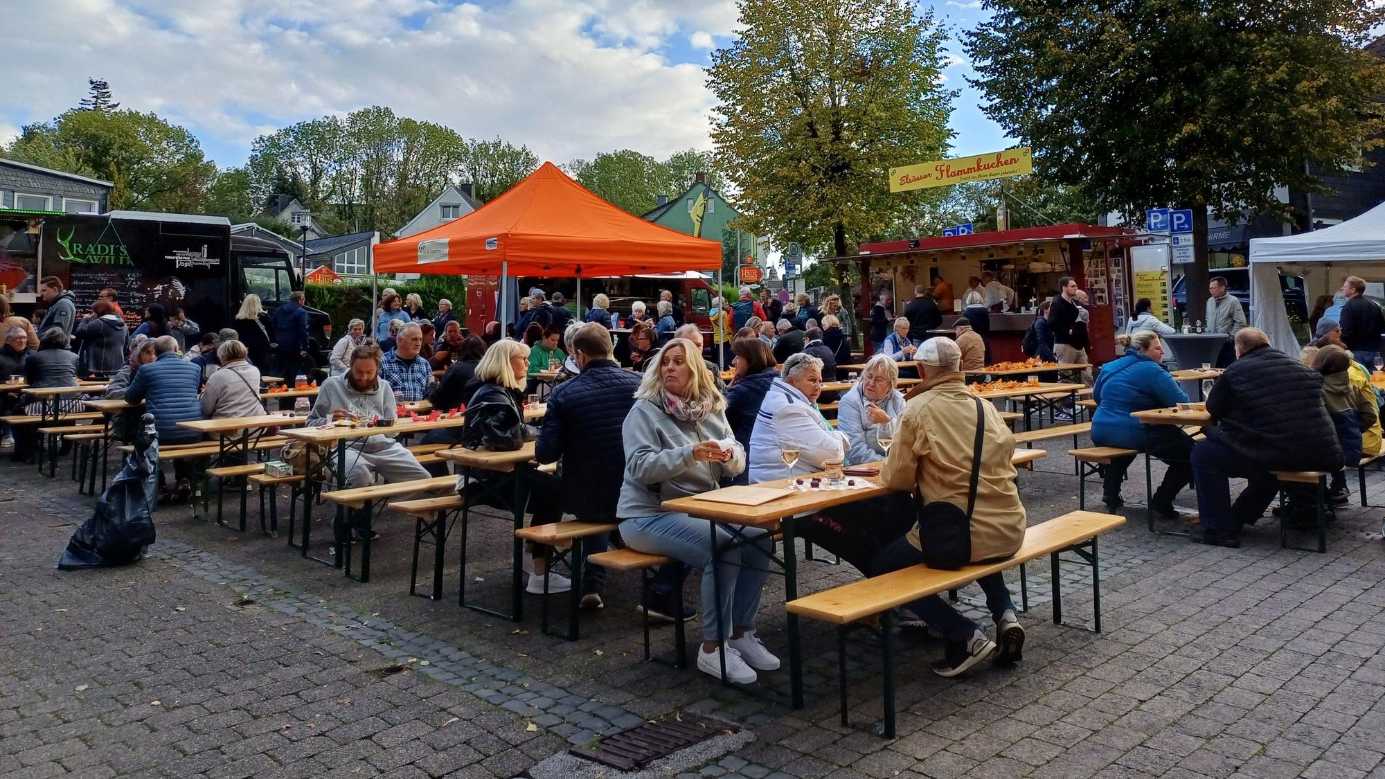 Menschen sitzen auf Bierbänken auf dem Burscheider Markt.