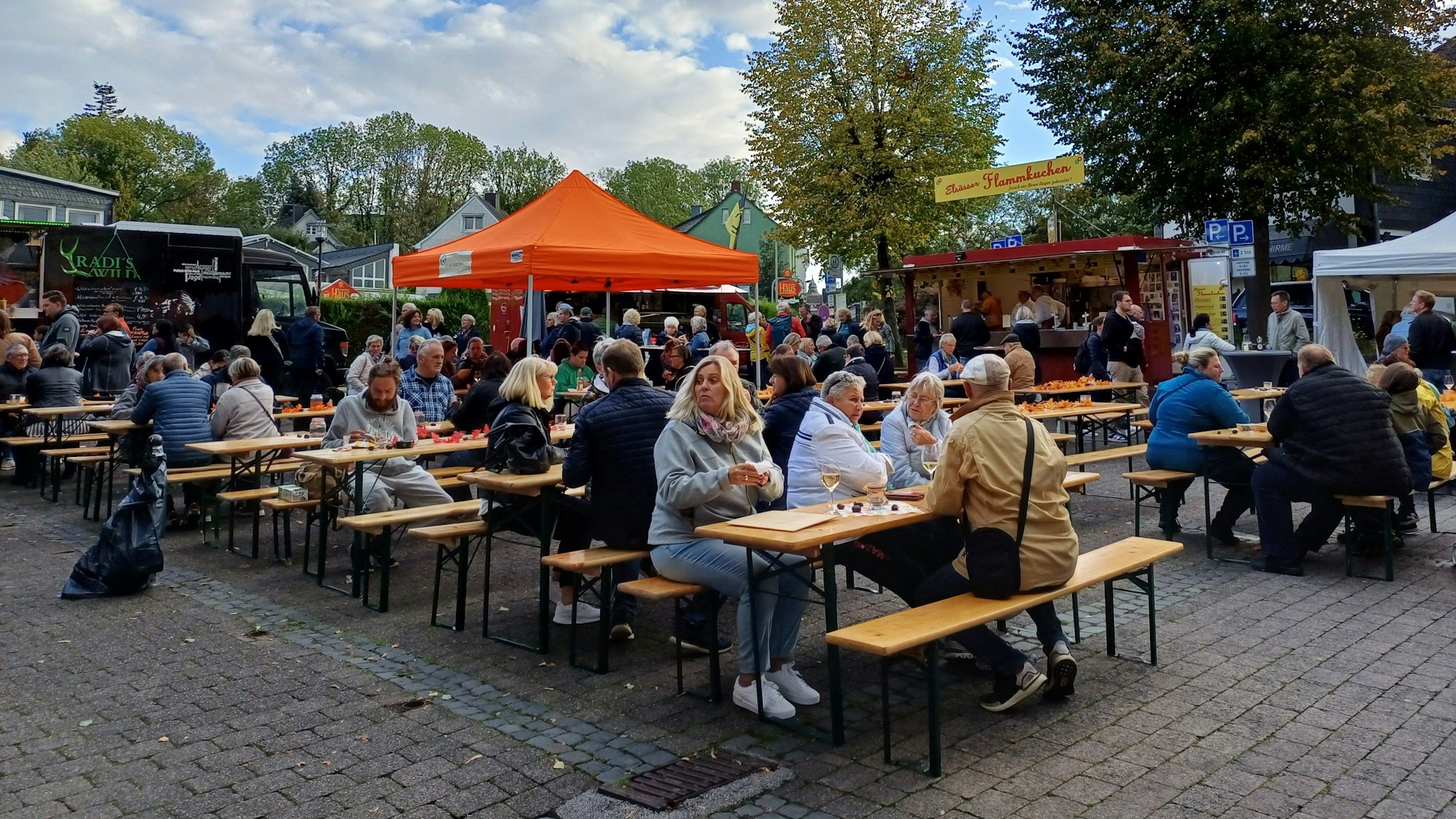 Menschen sitzen auf Bierbänken auf dem Burscheider Markt.