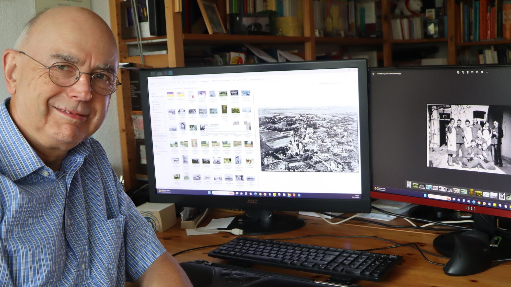 Hans-Peter Schneider sitzt an seinem Schreibtisch in seiner Wahlheimat Swisttal vor zwei Computerbildschirmen mit Schwarz-Weiß-Fotos.