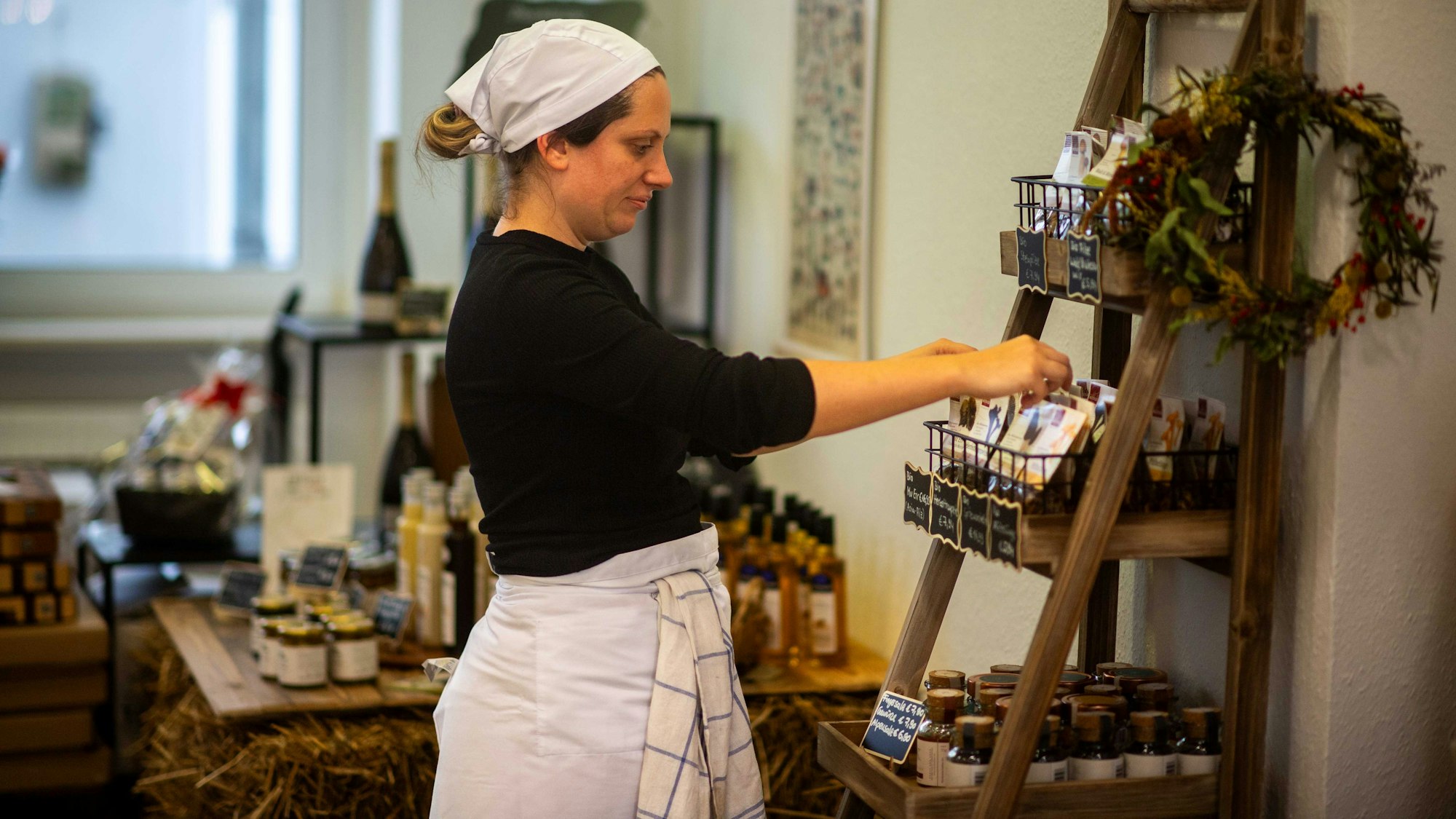 Das Bild zeigt Anika-Helena Wübben in ihrem Geschäft, wie sie ein Regal sortiert.