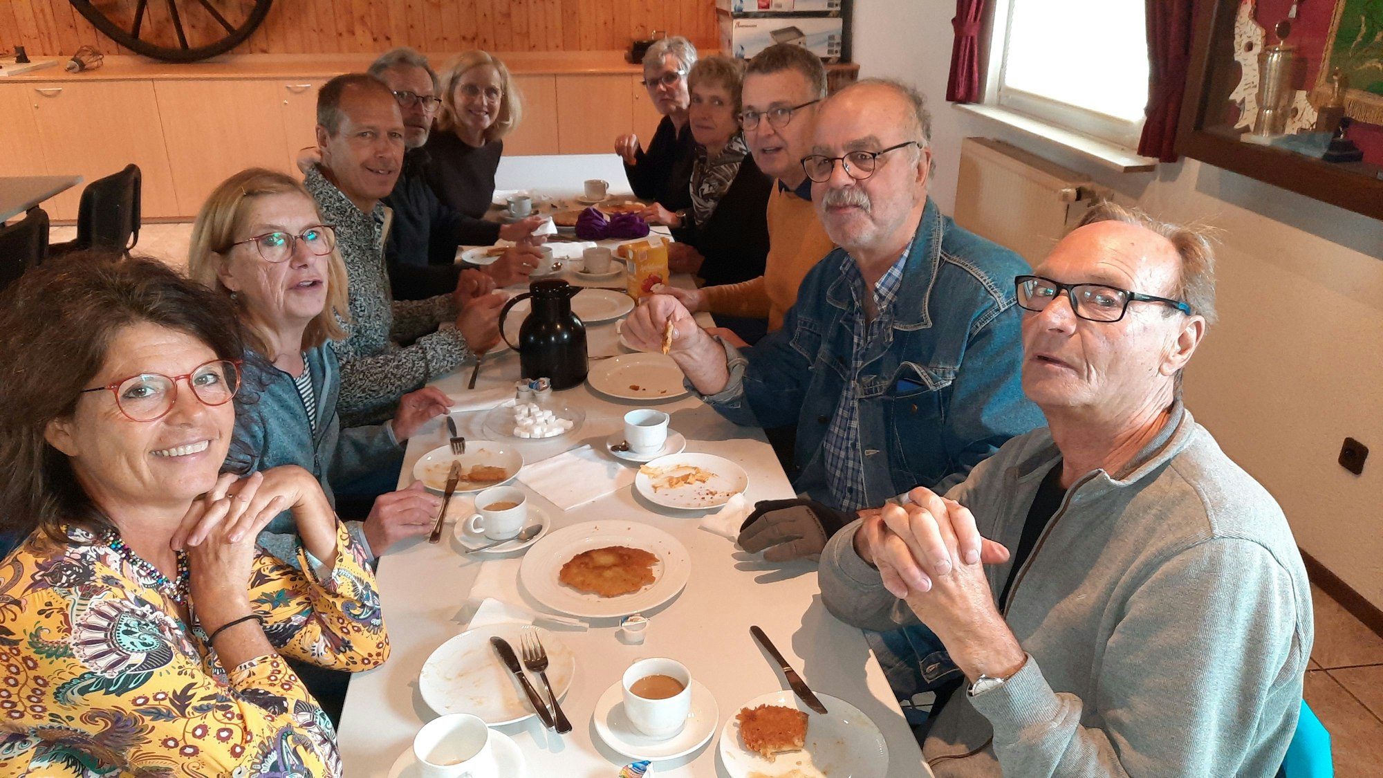 Eine Gruppe von Frauen und Männern sitzt an einem Tisch, auf den Tellern liegen Reibekuchen