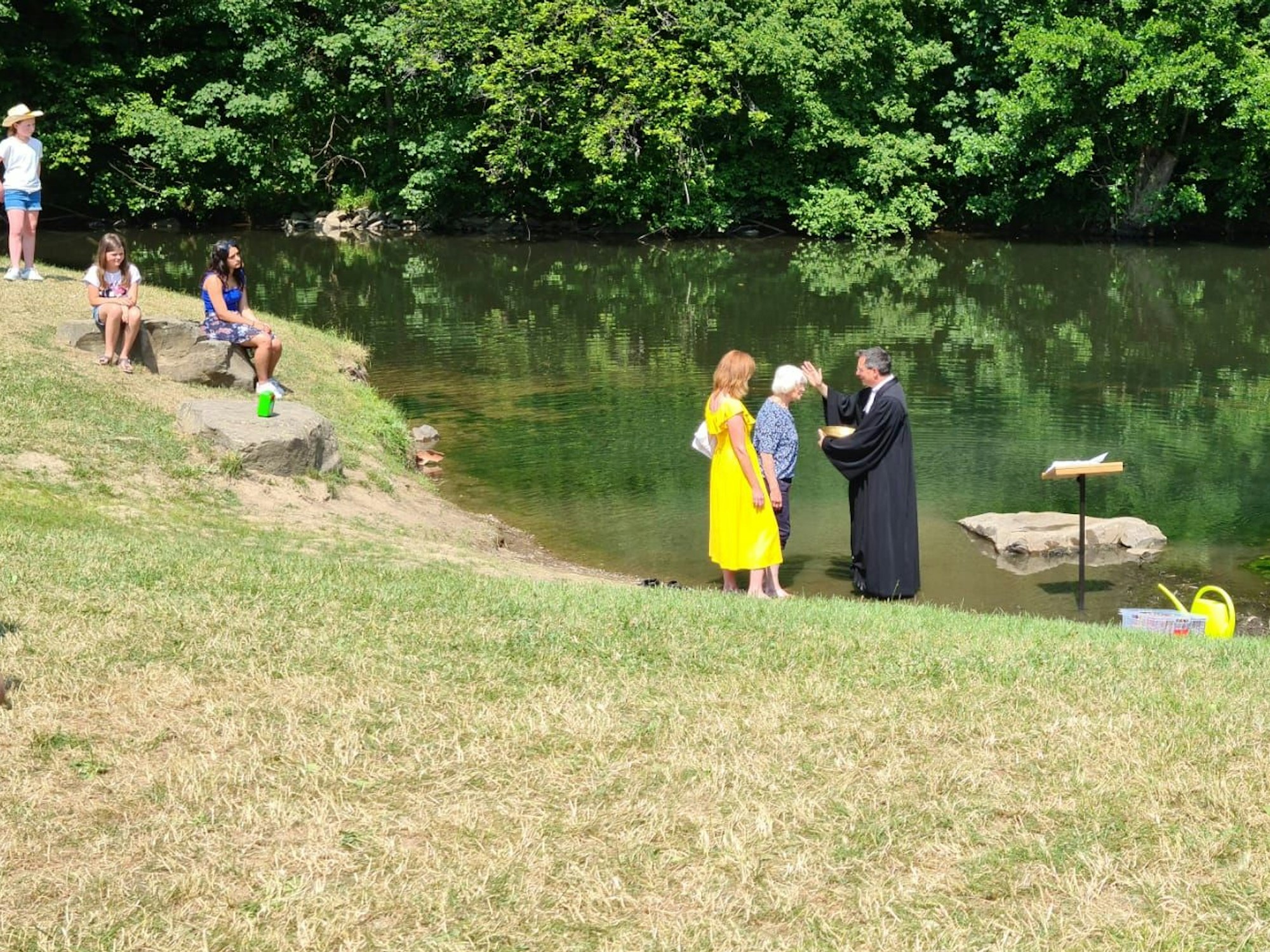 Pfarrer Henning Strunk steht mit Waltraud Geisen im Wasser der Agger bei Engelskirchen und tauft die Seniorin.