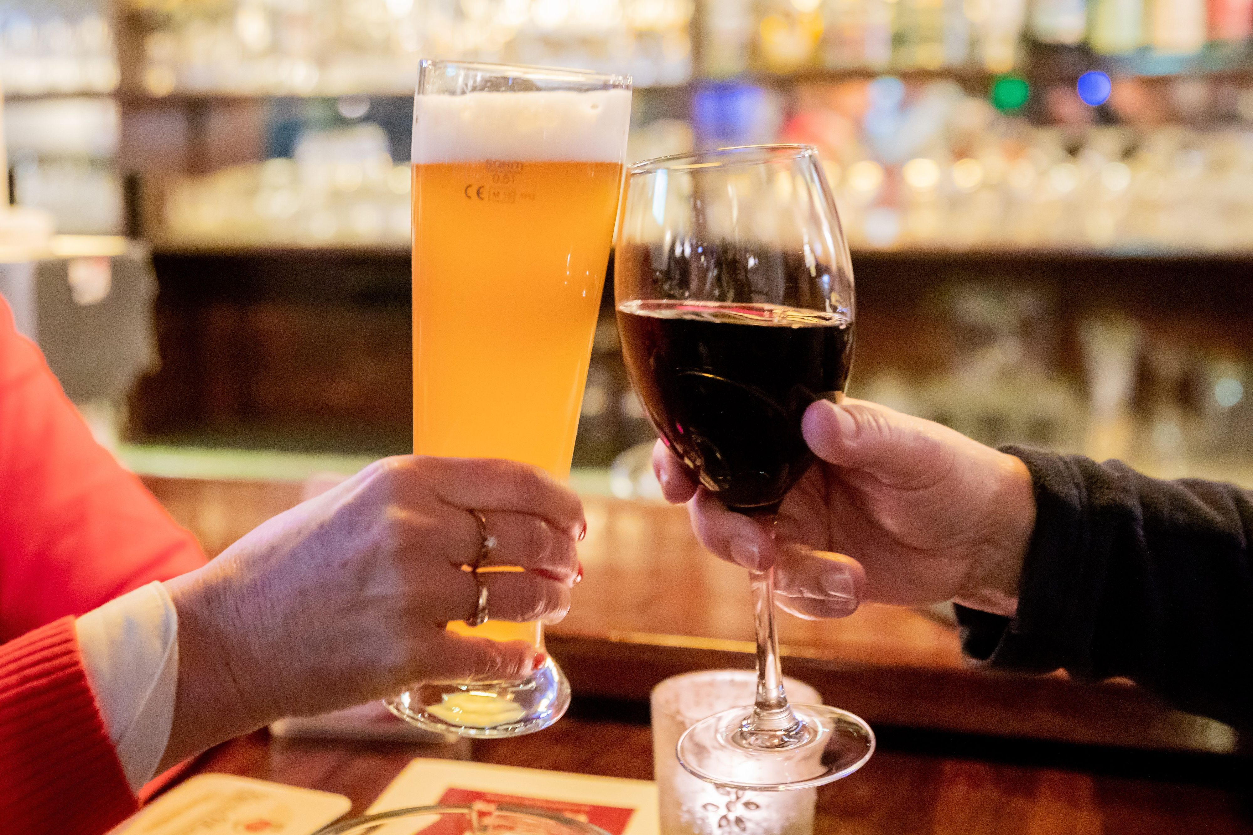 Ein Paar mit stößt mit Wein und Bier an.