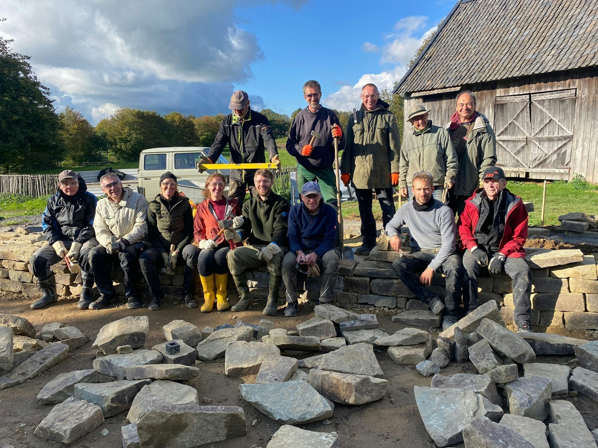Teilnehmer des Workshops sitzen auf der Trockenmauer