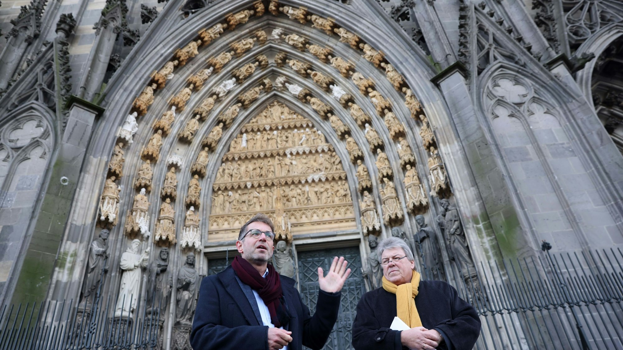 Zwei Männer stehen vor dem Eingang am Kölner Dom.