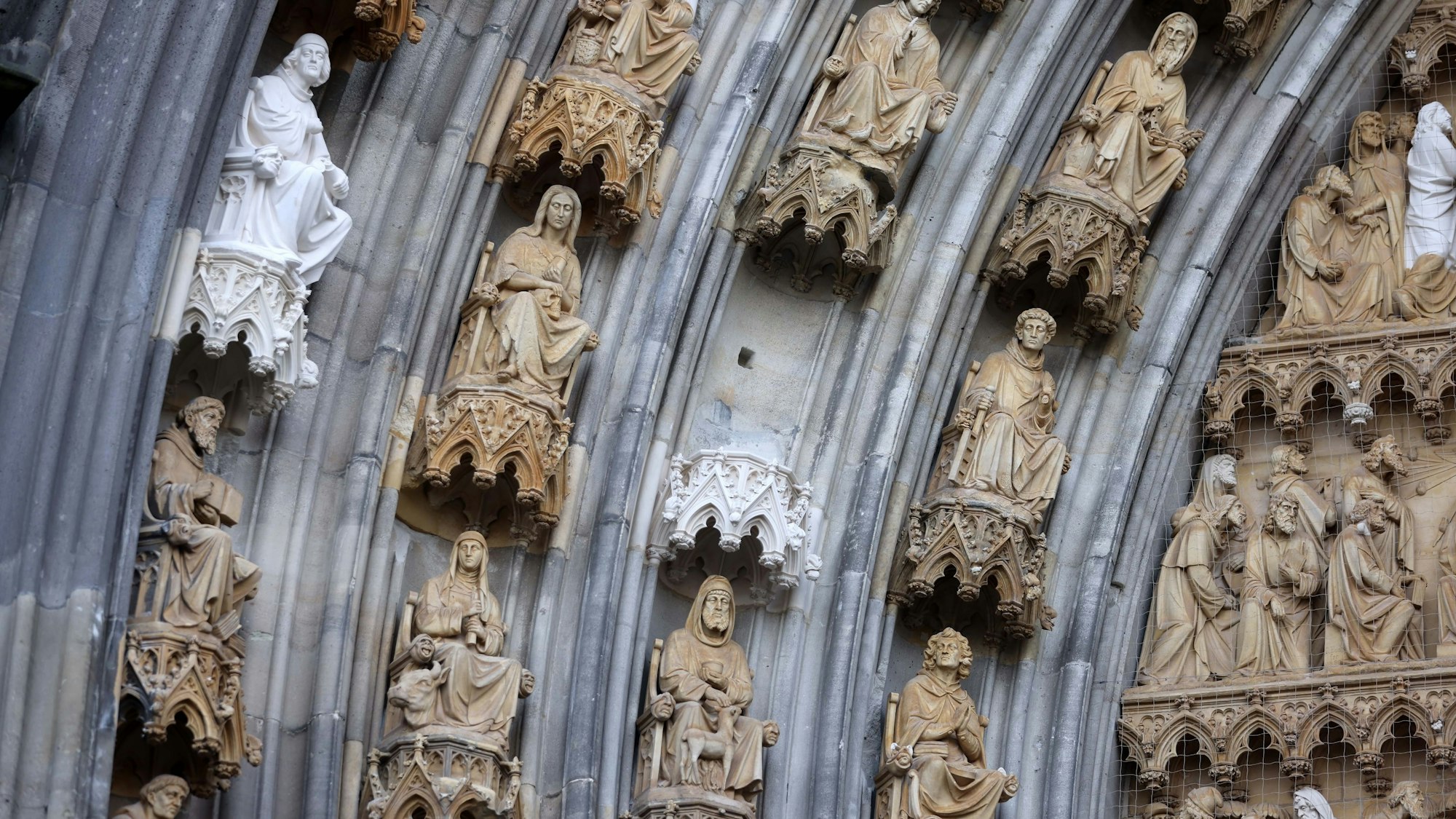 Mehrere Figuren sind am Kölner Dom angebracht. An einem Sockel fehlt eine Figur.