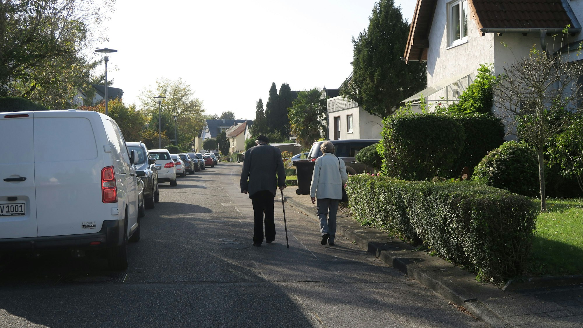 Ein älteres Paar geht auf der Fahrbahn einer Straße. Der Gehweg ist sehr schmal.