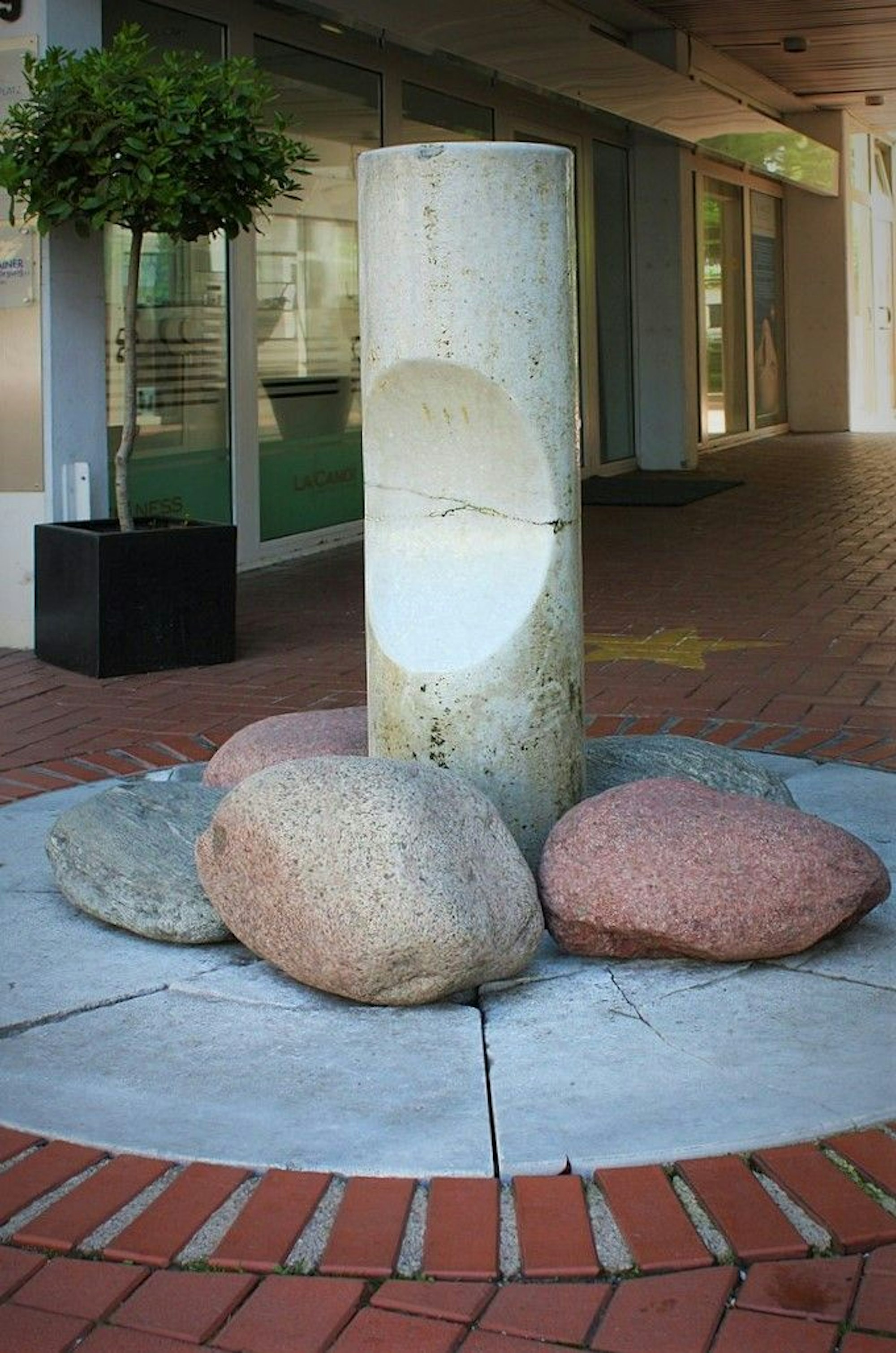 Eine Marmor-Brunnensäule mit 3 großen Kieselsteinen.
