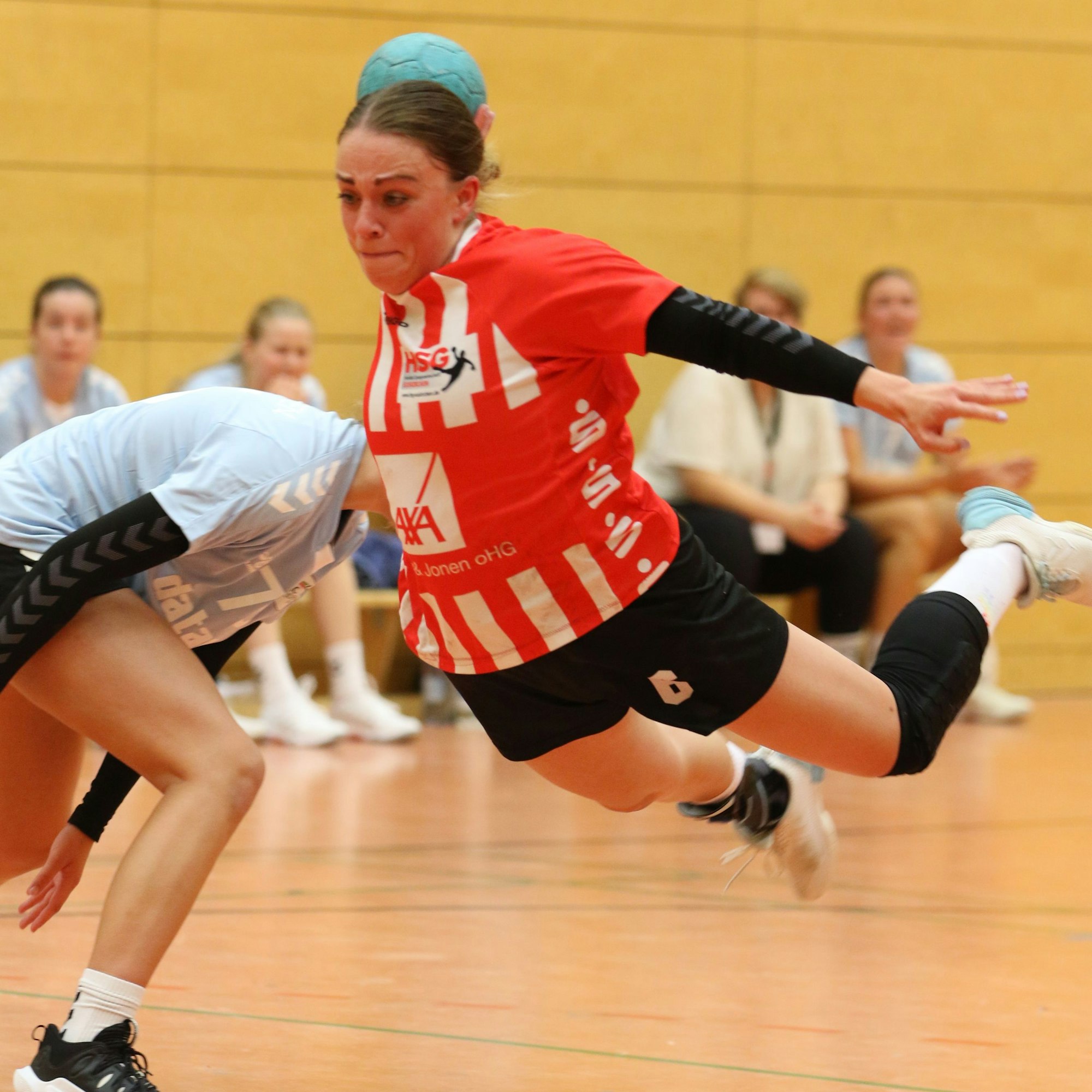 Eine Handballspielerin liegt quer in der Luft und setzt zum Wurf an.