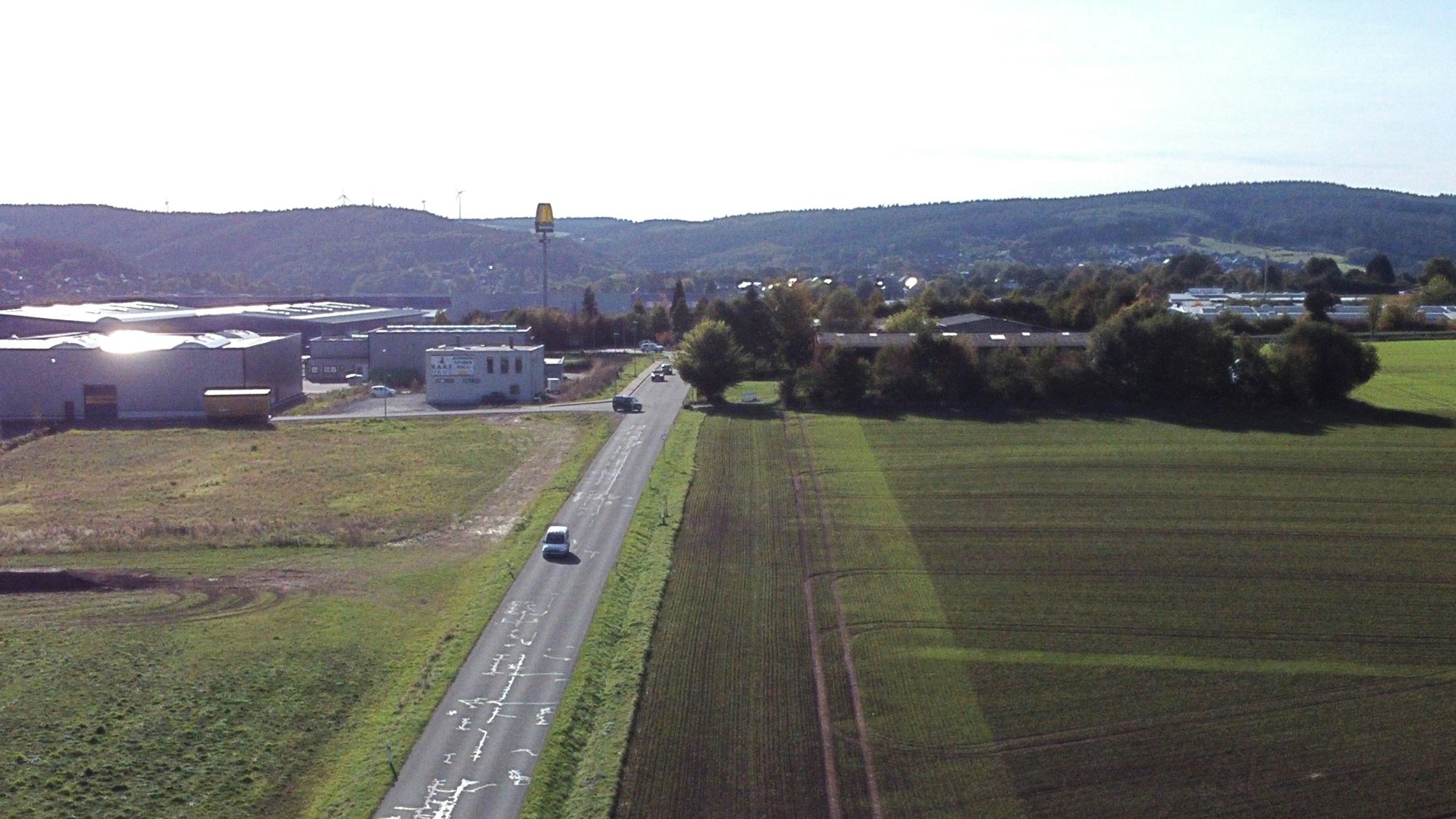 Zu sehen sind auf der Luftaufnahme der von Bäumen verdeckte Heidehof und die Freifläche daneben. Das Gelände wird von einer Straße begrenzt.