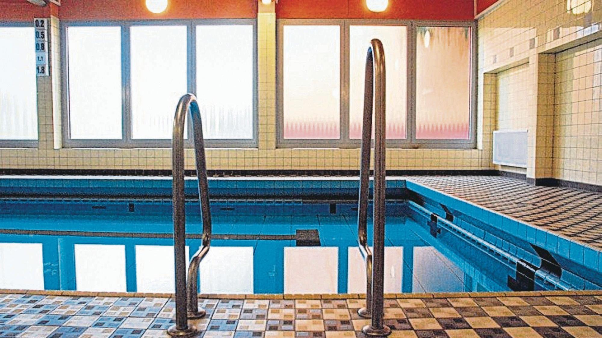 Ein Schwimmbecken mit Einstiegsleiter in einer Schwimmhalle.