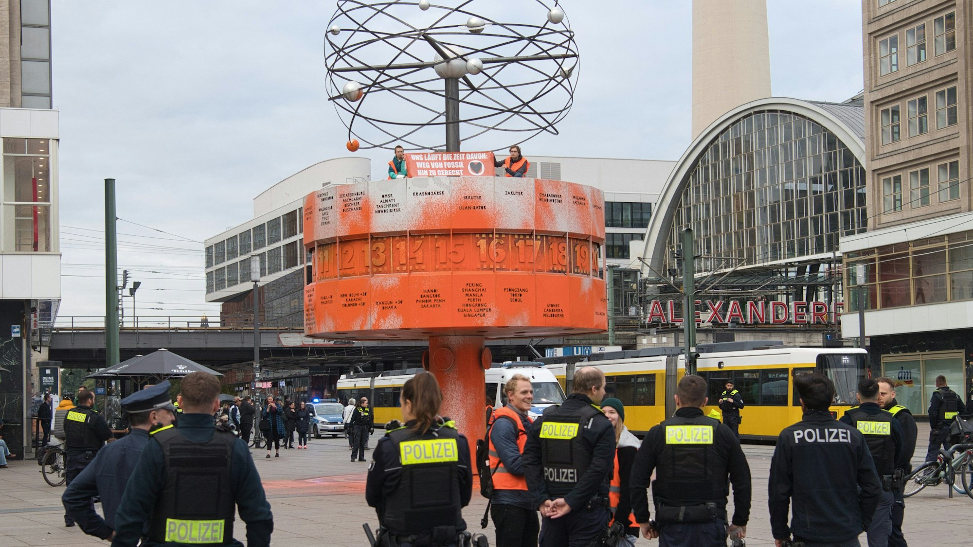 Klima-Aktivisten der Gruppe Letzte Generation haben die Weltzeituhr am Alexanderplatz in Berlin mit oranger Farbe besprüht. Die Polizei war im Einsatz.