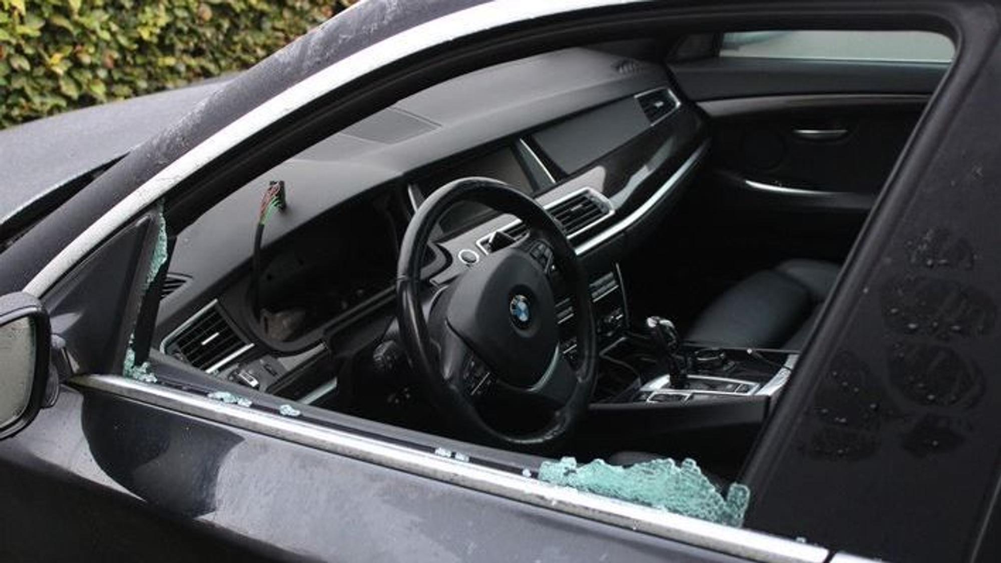 Eine eingeschlagene BMW-Fahrertür von der Seite. Scherben sind im Fensterbereich zu sehen, mittig das Lenkrad des Autos.